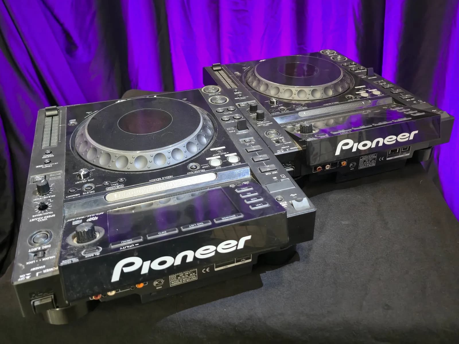 Twee Pioneer CDJ-mediaspelers voor een paars verlicht doek